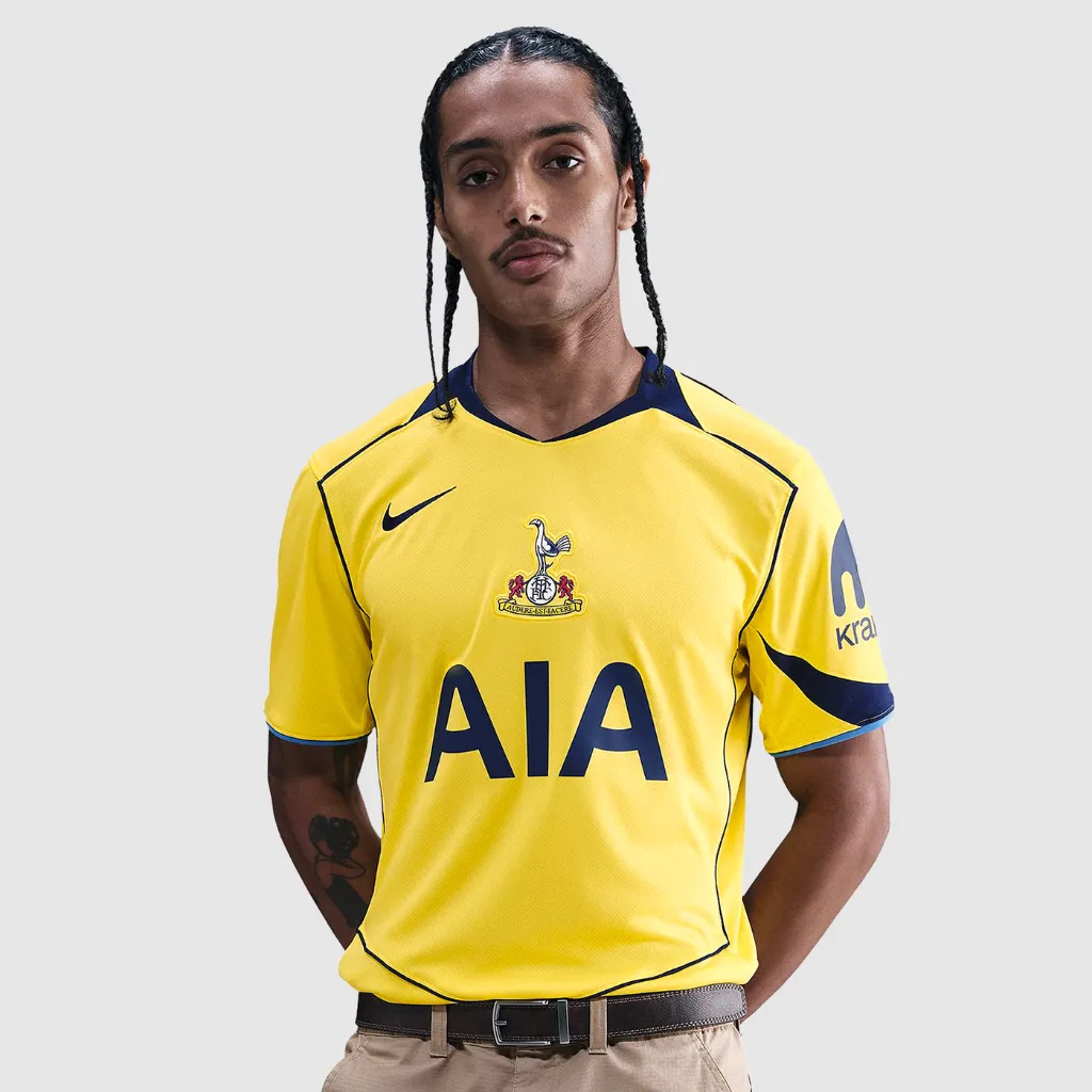 Camisa terceira do Tottenham Nike 2025 2026 amarela com escudo retrô centralizado, detalhes azul-marinho e design inspirado na era Total 90