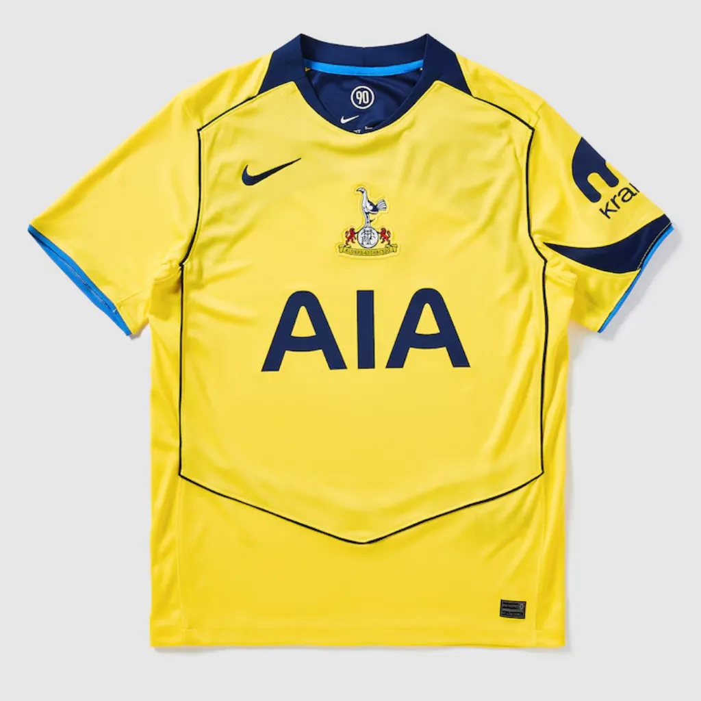 Camisa terceira do Tottenham Nike 2025 2026 amarela com escudo retrô centralizado, detalhes azul-marinho e design inspirado na era Total 90