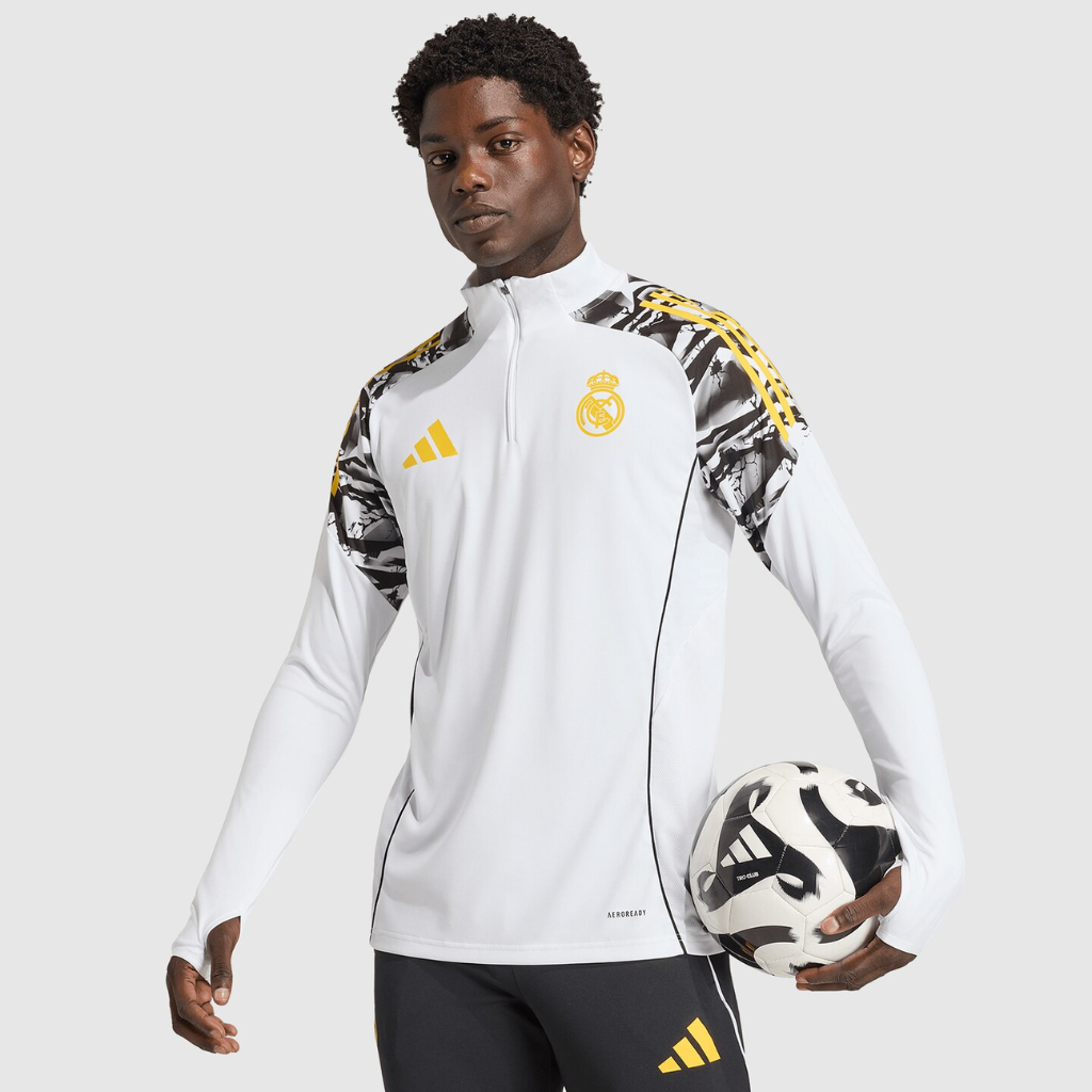 Close da camisa de treino Real Madrid x Marvel 2026 com escudo do clube e detalhes dourados.