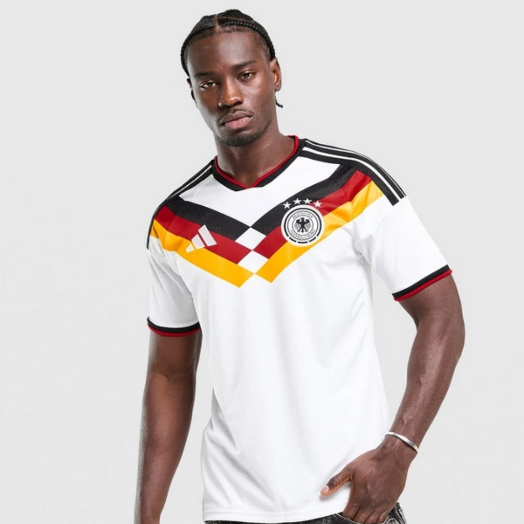Camisa home seleção alemã 2026 adidas branca com chevron preto, vermelho e dourado, inspirada nos títulos de 1990 e 2014.