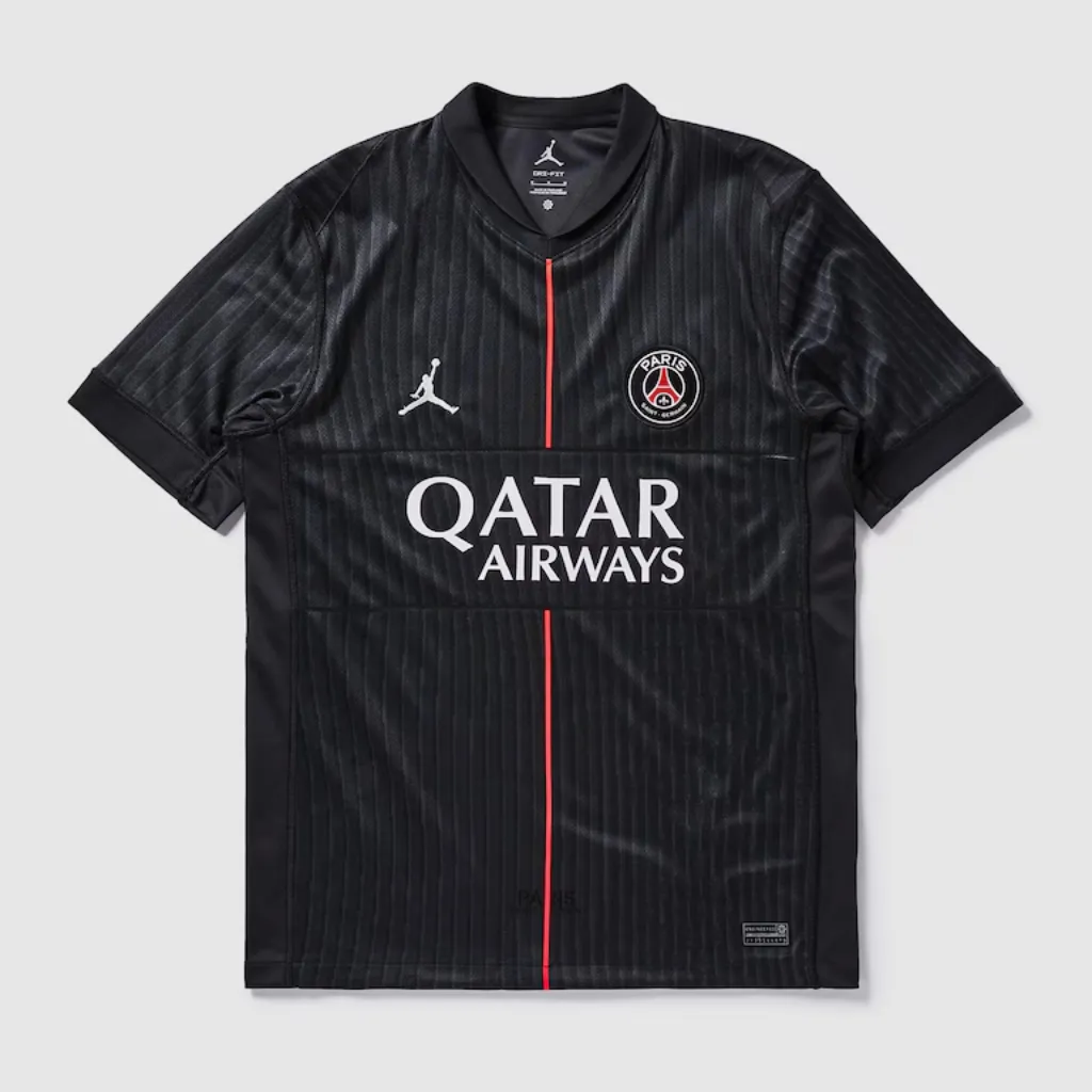 Quarta camisa do Paris Saint-Germain Jordan 2025/26 em tom Off Noir, com detalhes em rosa pérola, logo Jordan rosa claro e design minimalista inspirado na moda parisiense.