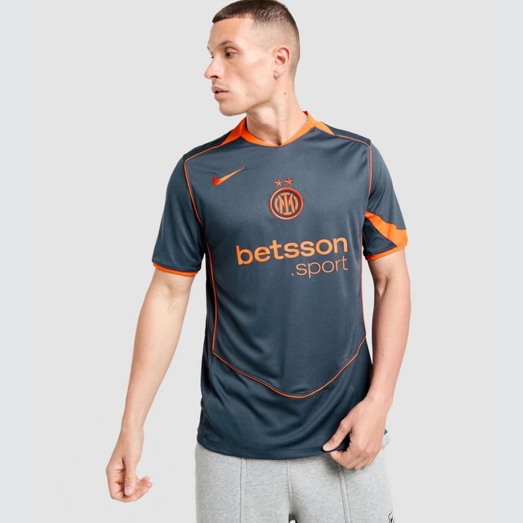 Camisa cinza e laranja Nike Inter de Milão 25/26 com arco frontal Total 90 e escudo centralizado em destaque.