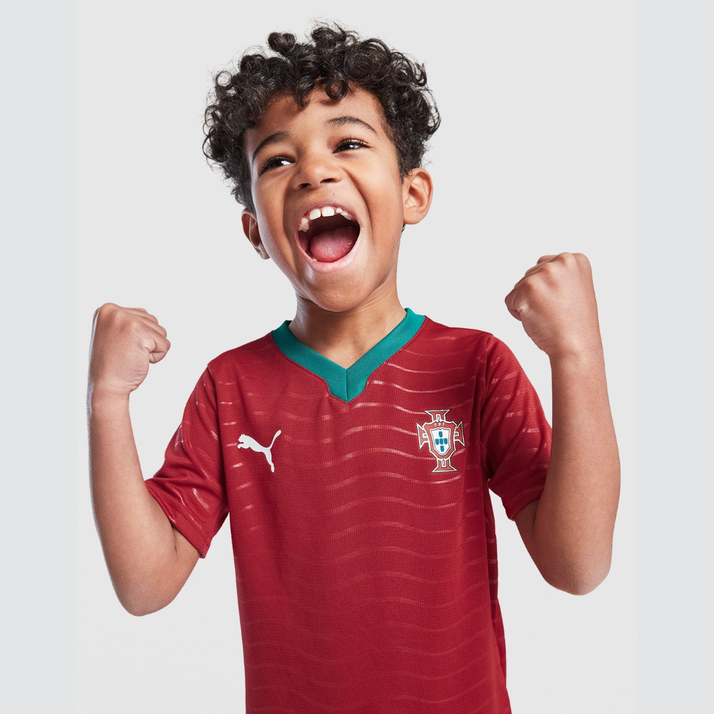 Criança comemorando com o kit infantil Portugal 2026, mostrando liberdade de movimento, leveza do tecido e ajuste ideal para brincadeiras.