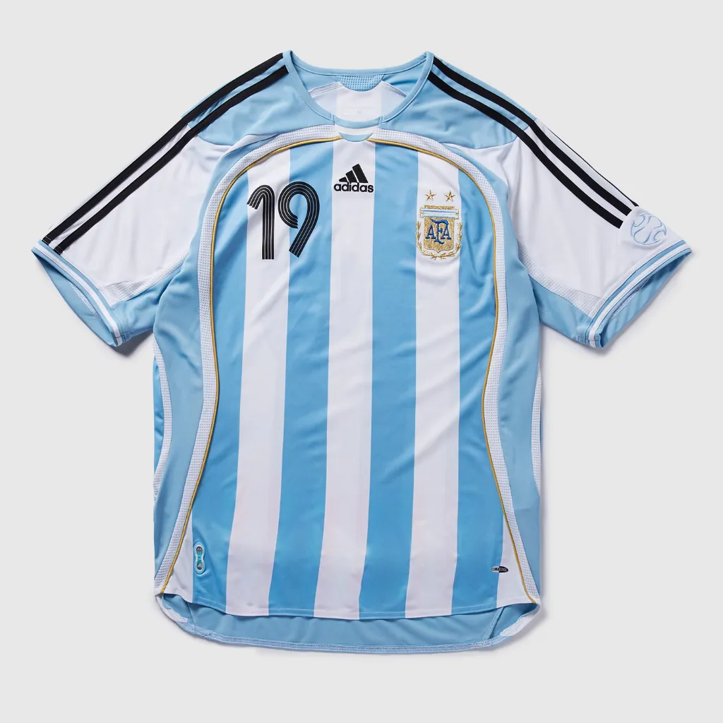 Camisa retrô Argentina 2006 esticada mostrando detalhes em dourado.