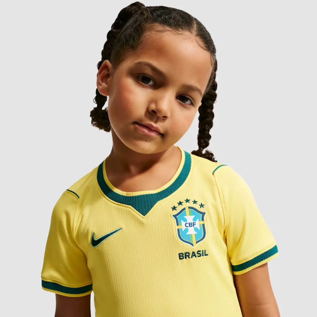 Conjunto infantil Brasil Nike 2026 amarelo canário com detalhes azul-esverdeados e padrão inspirado na bandeira do Brasil